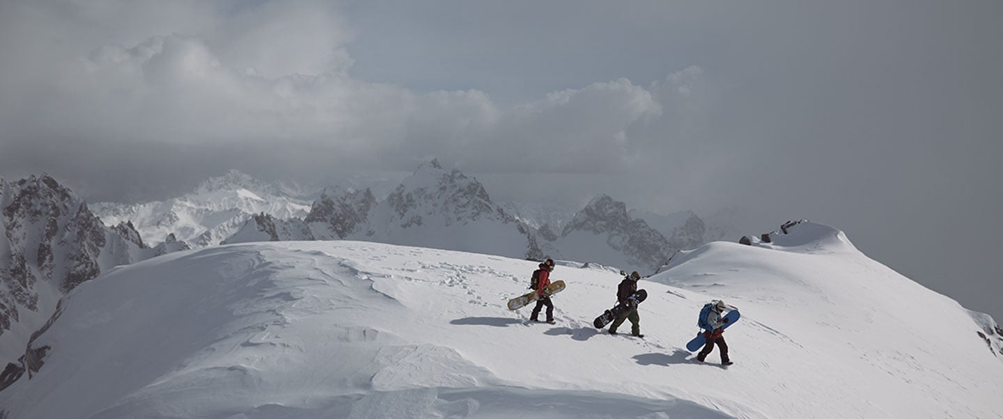 Snowboarders walking along a snowy mountain